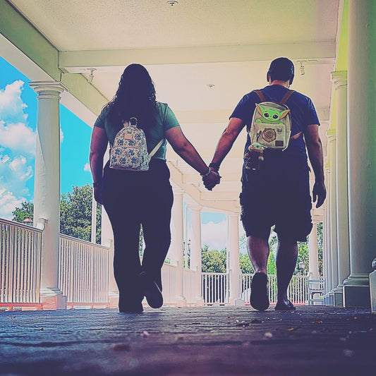 Couple Holding Hands while walking under a white covered wood walk way, blue skies and white puffy clouds in the sky