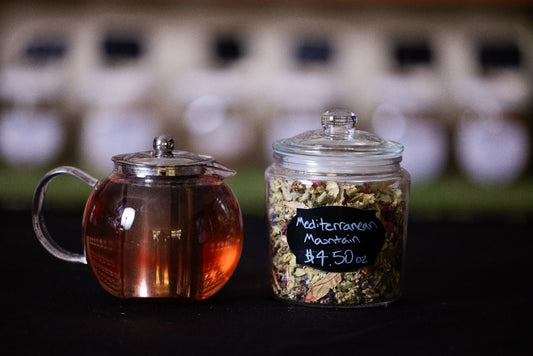 Brewed Tea in Tea Pot next to Glass Jar Filled with Loose Leaf Tea